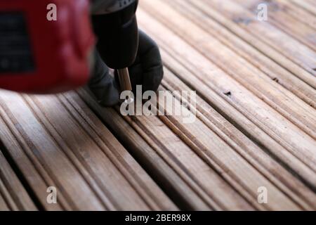 Fai da te costruzione di un portico / balcone pavimento con tavole di legno marrone a Espoo, Finlandia, febbraio, 2020. Persona che usa la macchina di perforazione per costruire il pavimento. Foto Stock