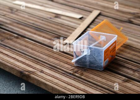 Fai da te costruzione di un portico / balcone pavimento con tavole di legno marrone a Espoo, Finlandia, febbraio, 2020. Scatola di viti con alcune viti sul pavimento. Foto Stock