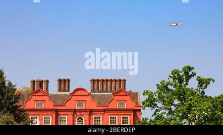 Il tetto e i camini del Palazzo al Kew Royal Botanic Gardens con un aereo che si avvicina all'aeroporto di Heathrow, Londra, Inghilterra Foto Stock