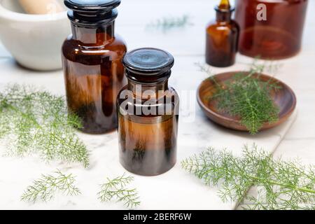 Olio essenziale di finocchio su bottiglie ambrate. Olio di erbe per la cura della pelle, aromaterapia e medicina naturale Foto Stock
