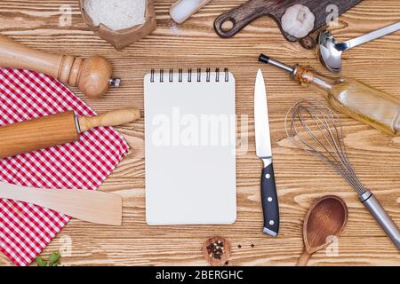 Carta per appunti vuota per testi o ricette e utensili da cucina su tavola di legno Foto Stock