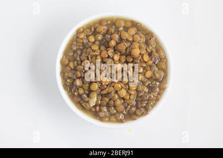 Lenticchie cotte in una ciotola su sfondo bianco Foto Stock