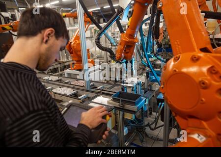 Riparatore che fa la riparazione su bracci robot automatici in fabbrica di automobili enorme, concetto industriale Foto Stock