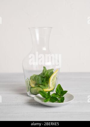 Vaso con cetrioli, fette di lime e foglie di menta all'interno per la ricetta dell'acqua di cetriolo. Concetto di detox fatto in casa. Verticale Foto Stock