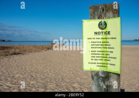 Covid-19 Virus Notice sulla spiaggia per la distanza sociale di sei piedi di distanza e gruppi dieci persone o meno Foto Stock