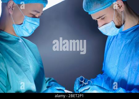 ritratto ravvicinato di due chirurghi operanti in sala operatoria con strumenti. In indumenti e maschere speciali sterili per chirurgia medica. Chirurgia di Foto Stock