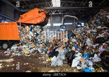 GRODNO, BIELORUSSIA - OTTOBRE 2018: Impianto di riciclaggio processo di carico rifiuti da camion rifiuti. Il manipolatore carica i rifiuti sul trasportatore per ulteriori azioni Foto Stock