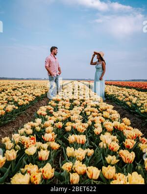 Campo di fiori di tulipano durante il tramonto crepuscolo nei Paesi Bassi Noordoostpolder Europa, giovane coppia felice uomini e donna con vestito in posa in campo di fiori in Foto Stock