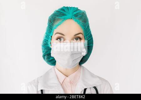 Concetto di medicina e sanità. Primo piano ritratto di una donna caucasica dottoressa, infermiera, lavoratore di laboratorio o scienziata in maschera protettiva facciale, cappuccio verde Foto Stock