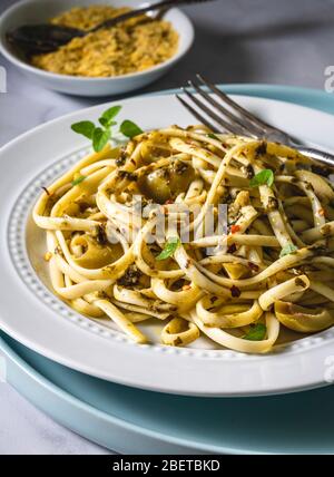 Piatto di pasta vegana. Fettuccine al pesto, olive verdi timo fresco e lievito nutritivo. Foto Stock