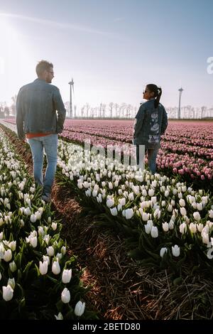 Campo di fiori di tulipano durante il tramonto crepuscolo nei Paesi Bassi Noordoostpolder Europa, giovane coppia felice uomini e donna con vestito in posa in campo di fiori in Foto Stock