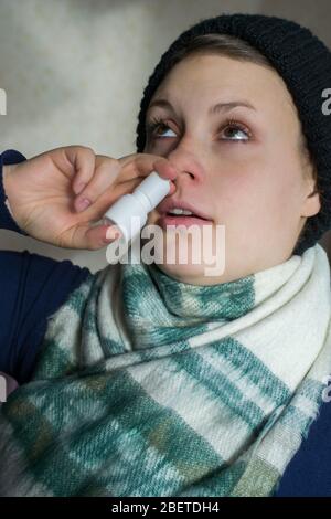 La ragazza spruzza lo spray dal naso che cola nel passaggio nasale Foto Stock