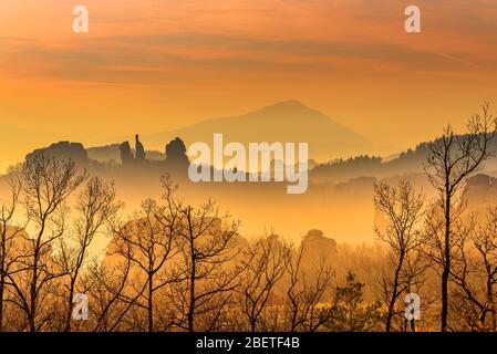 Incredibile tramonto di Hazy sulle sagome delle formazioni rocciose di arenaria dalla forma oddly nella città storica di Belogradchik, Bulgaria nord-occidentale Foto Stock