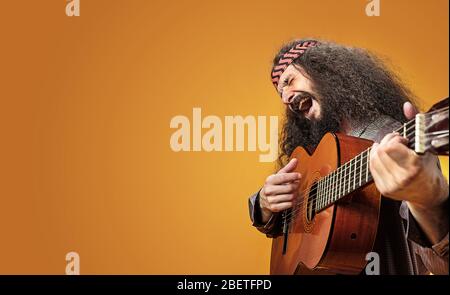 Allegro e skinny hippe che suona una chitarra Foto Stock