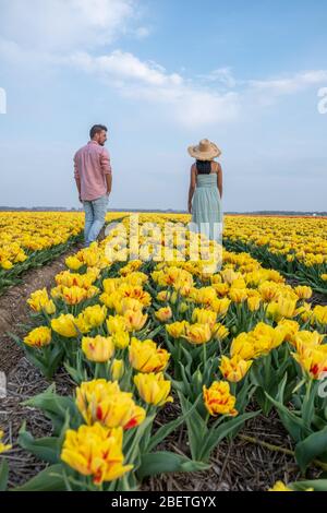 Campo di fiori di tulipano durante il tramonto crepuscolo nei Paesi Bassi Noordoostpolder Europa, giovane coppia felice uomini e donna con vestito in posa in campo di fiori in Foto Stock