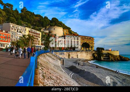 Nizza, Francia lungomare con spiaggia di ciottoli, torre Bellanda e collina castello in luce serale sulla Riviera francese. Foto Stock