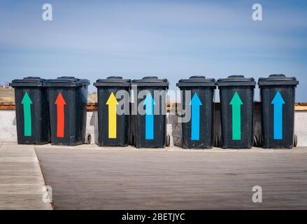 Bidoni per lettiere con frecce multicolore vicino al mare contro il cielo blu sul lungomare. Il concetto di pulito senza l'ecologia dei rifiuti della flora e f Foto Stock