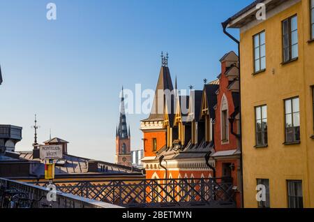 Tetti della Svezia tradizionale tipica ospita edifici con soffitta e pareti colorate sull'isola Sodermalm Soder, guglie della chiesa di Riddarholmen a Gamla S. Foto Stock