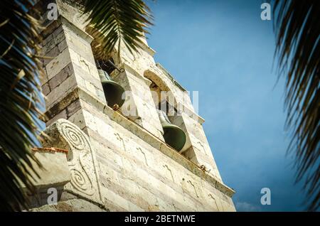 Vista del campanile della chiesa della Santa Trinità attraverso foglie di palma di fronte al cielo blu, Budva, Montenegro Foto Stock