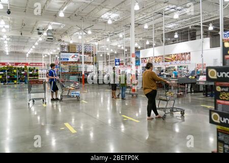 Kennesaw, GA / USA - 04/05/20: Persone mascherate in attesa in linea al checkout esercitandosi a distanza sociale in piedi 6 piedi di distanza via linee a terra a Cos Foto Stock