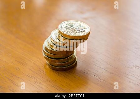 Nuove monete da una sterlina in una pila su un tavolo Foto Stock