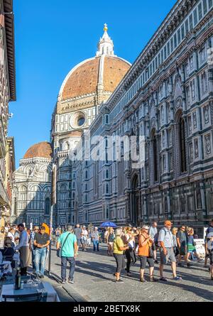 Turisti che passeggiano lungo Piazza del Duomo di fronte alla Cattedrale di Firenze al sole estivo, in Italia Foto Stock