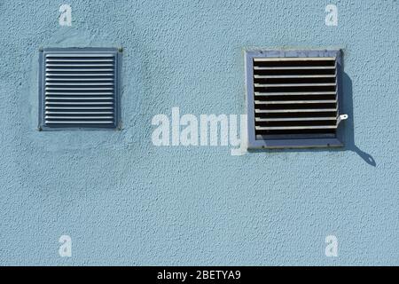 griglia di ventilazione quadrata in metallo, con parete blu, vista ravvicinata, per aria fresca e raffreddamento Foto Stock