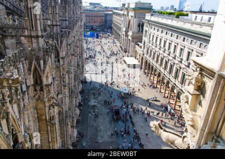 Una folla di piccole figure di molte persone si trova a piedi in Piazza del Duomo vicino alla Galleria Vittorio Emanuele II nel centro storico della città, vista dall'alto Foto Stock