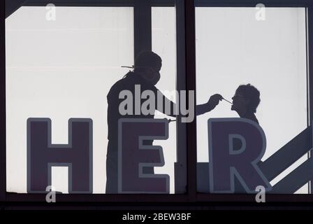 I dipendenti del Dell Seton Medical Center vengono controllati per verificare l'eventuale presenza di temperature elevate e segni di infezione da coronavirus prima di entrare nella struttura da un ponte sospeso sulla 15th Street di Austin. Il Texas ha visto quasi 15,000 casi e 318 morti a causa del COVID-19 a metà aprile. Foto Stock