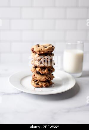 Pila di biscotti al cioccolato e latte su bancone in marmo bianco. Foto Stock