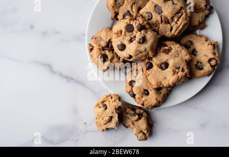 Primo piano dei biscotti appena sfornati con scaglie di cioccolato sul piatto dall'alto. Foto Stock