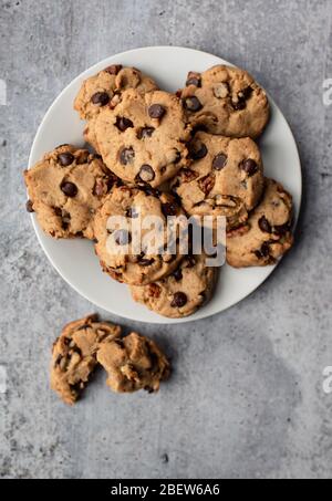 Primo piano dei biscotti appena sfornati con scaglie di cioccolato sul piatto dall'alto. Foto Stock