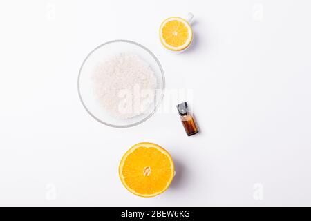 Scrub corpo anticellulite ingredienti sale marino, olio essenziale di limone e arancio, piatto su fondo bianco. Foto Stock