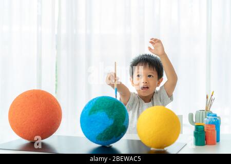 Bambino asiatico prescolare pittura della luna imparare circa il sistema solare a casa, Homeschooling e apprendimento di distanza. Foto Stock