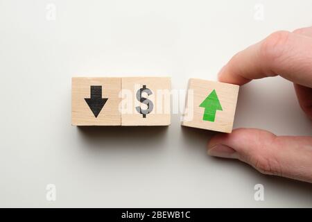 Concetto di crescita del dollaro in aumento - mano tiene cubo con freccia verde accanto al segno del dollaro. Primo piano. Foto Stock