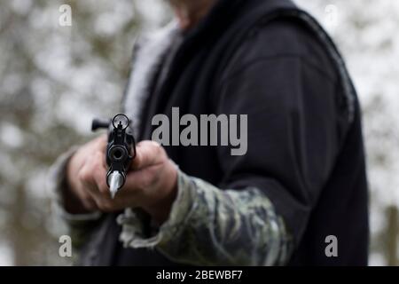 Hunter che punta il fuce con baionetta al visore. Fissando un barile di una pistola. Uomo che tiene il fucile e lo punta giù alla vittima. Concetto di caccia al cervo. Foto Stock