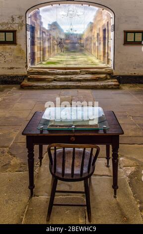 Vista dal tavolo e dalla sedia della stazione delle guardie che guarda lungo la solitaria confino hall Way alle rovine della colonia penale di Port Arthur in Tasmania, Australia. Foto Stock