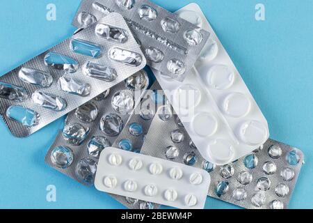 Un mucchio usato blister confezioni di pillole su sfondo blu. Blister per uso medico aperti e vuoti senza pillole vista dall'alto. Concetto medico e sanitario. Foto Stock