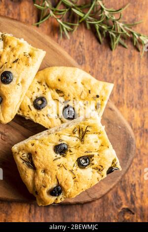 Focaccia italiana fatta in casa. Dolci tradizionali italiani con olive su tavola di legno. Foto Stock