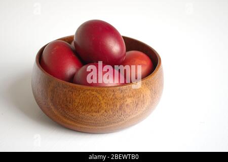 Primo piano delle uova di Pasqua in ciotola di legno su sfondo bianco Foto Stock
