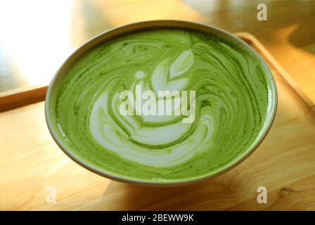 Closeup una tazza di latte caldo di tè verde Matcha su un vassoio di legno Foto Stock