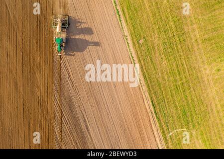 Vista aerea del campo di aratura del trattore. Trattore in funzione su un campo nell'angolo superiore sinistro Foto Stock