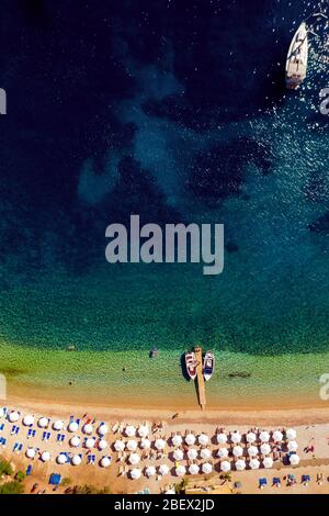 Aereo di paradiso spiaggia mediterranea in Grecia. Spiaggia con ombrelloni e bella acqua di mare turchese da un drone Foto Stock