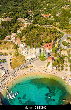 Spiaggia soleggiata in Grecia villaggio Paleokastritsa. Spiaggia trafficata su una riva del mare mediterraneo. Isola di Corfù Foto Stock