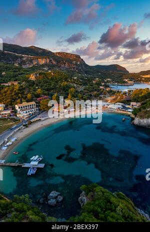 Vista aerea sulla spiaggia mediterranea di Paleokastritsa Corfu. Paesaggio serale di resort in Grecia. Una bella baia con ristoranti e barche Foto Stock