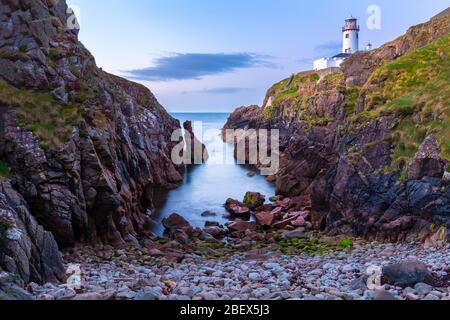 Vista di un tramonto dalla baia sotto il faro di Fanad Head (Fánaid), contea di Donegal, regione dell'Ulster, Irlanda, Europa. Foto Stock