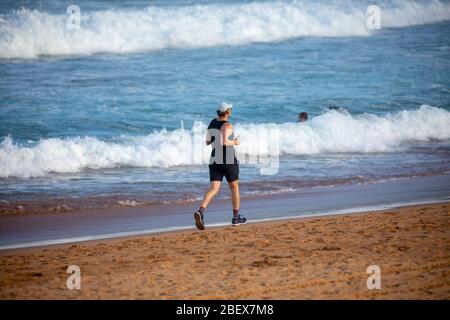 Uomo australiano jogging sulla spiaggia di Sydney avalon durante lo scoppio di coronavirus per rimanere in forma, Sydney, Australia Foto Stock