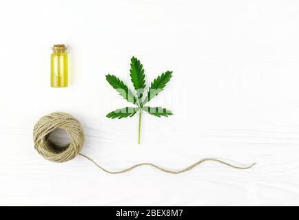 Corda di cannabis, olio e pianta di canapa su sfondo di legno bianco. Foto Stock