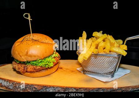 Un hamburger di pollo croccante impanato servito insieme ad una porzione di patatine fritte Foto Stock