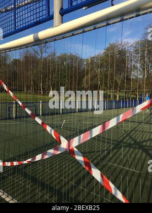 Glasgow, Regno Unito, 16 aprile 2020. Un uomo si esercita la mattina presto nel Queen's Park, accanto a recinzioni e nastro che mostra le restrizioni in atto su un campo di pallacanestro / calcio, per garantire il corretto distanziamento sociale del pubblico e per prevenire le riunioni di persone, durante l'attuale crisi di salute Coronavirus COVID-19 pandemic. Photo credit: Jeremy Sutton-Hibbert/ Alamy Live News. Foto Stock